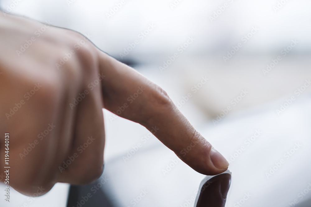 Poster man's finger operating a modern tablet device placed on a desk, within the blurry contours of a well
