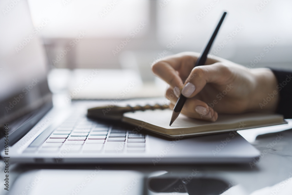 Aufkleber sharp view of a woman's hand transcribing in a notepad on a cutting-edge laptop, with a defocused ba