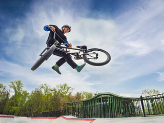 BMX bicycle rider doing stunt Tailwhip in quarter pipe. Skilled BMX freestyler athlete jumping over...
