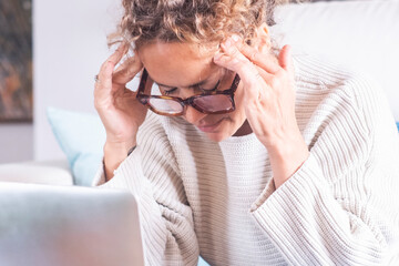 A woman working in her home office, dressed casually, looking frustrated but focused, using her laptop to solve work problems, navigate websites, and engage in online tasks for her digital business 