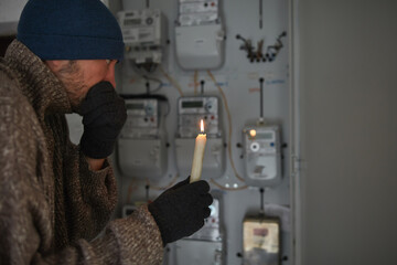 Checking the electricity power meter with a candle in cold winte