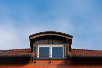 Rooftop features a distinctive architectural design with a small balcony and expansive windows. The blue sky serves as a backdrop, highlighting the contemporary lines of the structure.