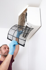 Man cleaning and maintaining air condition unit at home.