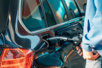 young man filling car gas tank at service station