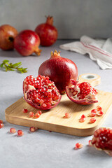 Fresh pomegranates, ripe red pomegranate slices on cutting board.