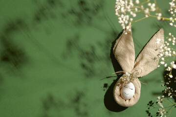 Happy Easter background with copy space. Beautiful festive Easter composition with napkin Easter Bunny and spring flowers, warm sunlight with soft shadows.