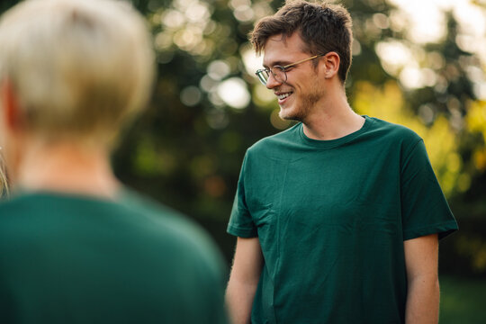 Young man wearing glasses smiling during charity event with colleagues