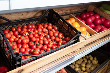 fresh ripe cherry tomatoes in box on supermarket shelf in grocery department. organic vegetables, healthy food. Yellow tomatoes and Mikado on background, unfocused
