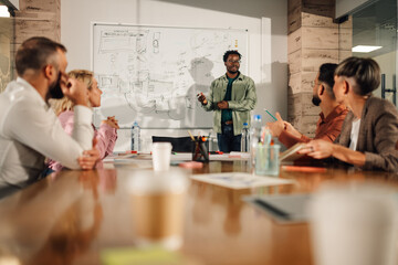Young african american manager presenting new project to colleagues in meeting room