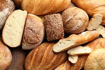 Whole and cut loafs of bread on table, closeup