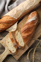 Fresh baguettes and spikes on wooden table, flat lay
