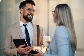 Businesspeople having conversation while holding digital tablet and coffee cup