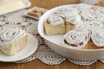 Delicious frosted cinnamon rolls on wooden table, closeup