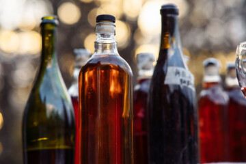 Close - up of group of glass transparent bottles of homemade berry and fruit wine. Natural.