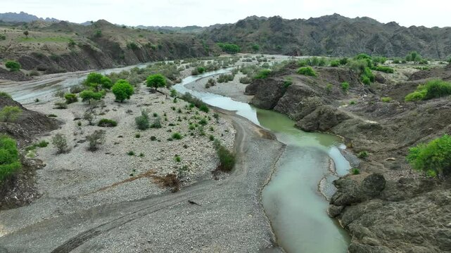 Aerial pull back shot capturing hilly landscape of Balochistan, Pakistan on an overcast day.