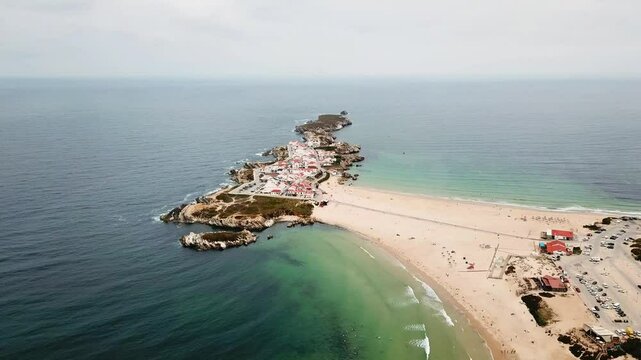 Stunning aerial perspective of Baleal, Portugal, featuring its unique coastal peninsula, sandy beaches, clear waters, and a charming seaside village with vibrant red rooftops