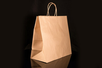 Recyclable craft paper bag for purchases, gifts and takeaway food mock up on black background. Environmentally friendly than single-use plastic bags