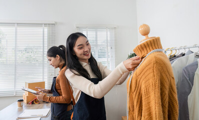 Women fashion designers adjusting a cozy sweater on a mannequin, showcasing teamwork and creativity in a boutique