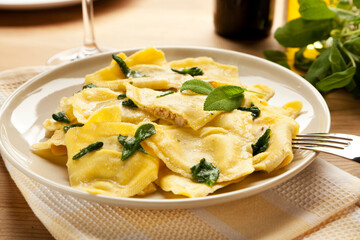 Plate of ravioli pasta filled with porcini and truffles, garnished with sage