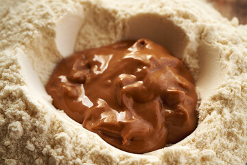 Whey protein powder and peanut butter in a bowl - preparation of homemade protein chocolate bars
