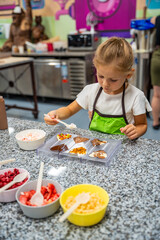 Little girl learning how to cook in a cooking class. Handmade dessert. Making chocolate candy, Child filling heart shaped mold with chocolate