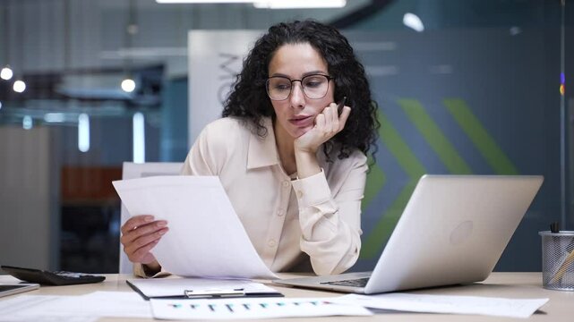 Overworked businesswoman is tired of doing paper work sitting at workplace at desk in a modern business office. Exhausted female financier overtired burnout deadline. Female employee has apathy