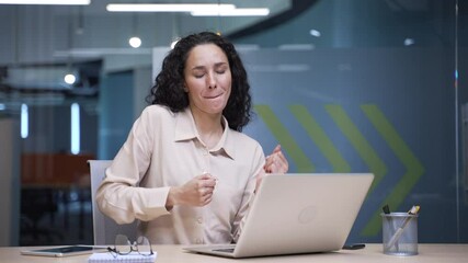Happy businesswoman finished work on laptop and dances while sitting at workplace in business office. Smiling joyful female employee celebrating success, cheerfully rejoices in achievement. Work done - Powered by Adobe