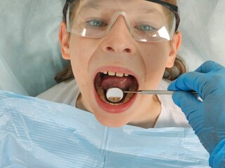 Young patient receiving dental examination in a clinic setting with hygienist assistance
