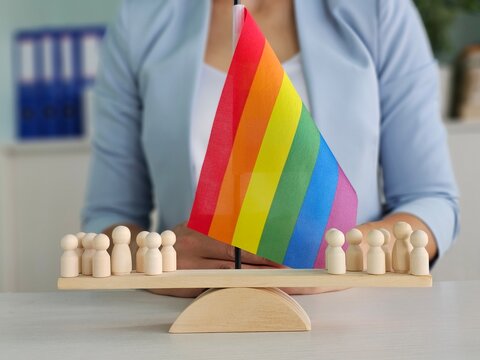 Rainbow flag displayed with figurines representing diversity in an office setting - Powered by Adobe