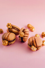 French macarons with chocolate cream and popcorn on top isolated on pink background	