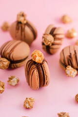 French macarons with chocolate cream and popcorn on top isolated on pink background	