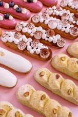 different types of eclairs decorated with cream isolated on pink background