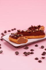 chocolate eclair decorated with chocolate cream and gold cut in half on a plate
