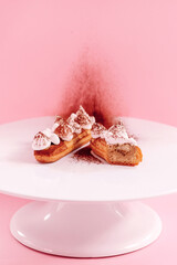 eclair decorated with white cream on the white plate sprinkled with cocoa powder 