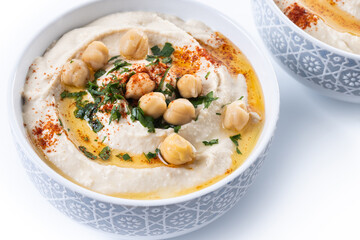 Chickpea hummus with olive oil, parsley and paprika in bowl isolated on white background