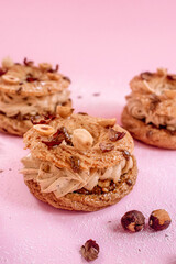 Paris Brest French dessert filled with nut and almond creme mousseline sprinkled with hazelnuts isolated on a pink background