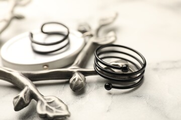 Stylish presentation of rings on white marble table, closeup