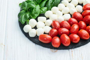 Basil leaves , cherry tomatoes and mozzarella cheese . In form italian flag food photography