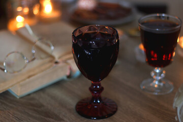 Books, lit candles, red wine, snacks and various deocration on the table. Dark academia or Halloween concept. Selective focus.