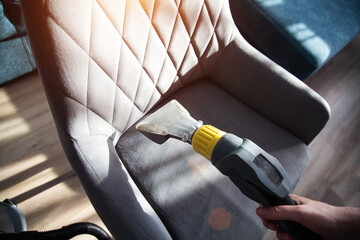 Services for washing and cleaning upholstered furniture with a vacuum cleaner. Cleaning dirty gray...