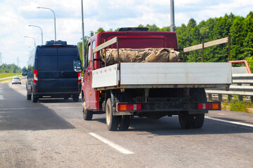 An open flatbed truck drives on a highway in summer. Transportation of goods up to 5 tons. Rental of trucks for regional and international transportation. Copy space for text