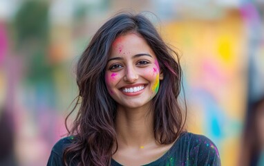 Fototapeta premium A young woman smiling brightly, her face and hair splashed with vivid Holi colors, set against a blurred festive backdrop