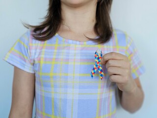 Child holding colorful ribbon symbolizing support for awareness causes indoors