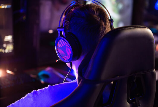 Professional gamer is playing a computer game on PC at cyber club. Player is participating in E-sports competition at gaming cafe. Gamer playing tactical shooter game during cyber sport tournament