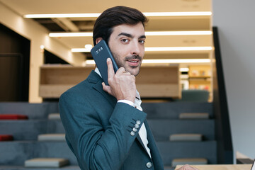 Positive businessman with laptop speaking on mobile phone