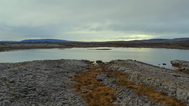Stunning aerial pan shot close to the ground featuring a large seasonal lake in the Burren. County Clare