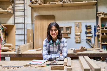 Young carpenter smiling confidently in a busy wooden workshop
