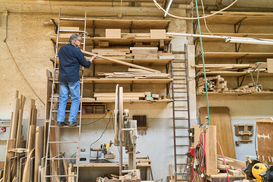 Experienced worker organizing lumber in a busy workshop setting