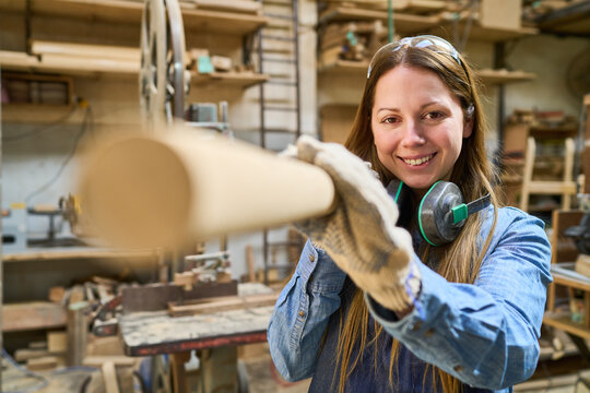 Young woman works with wood in a lumberyard workshop - Powered by Adobe