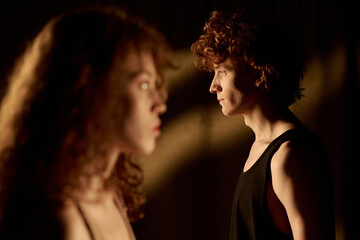 Side view of curly haired Caucasian couple looking in different ways after fight, focus on man with...